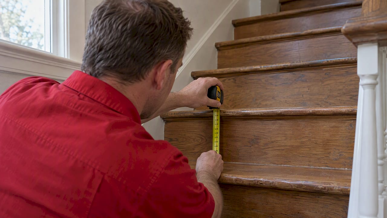 Homeowner measuring rise on hardwood stairs