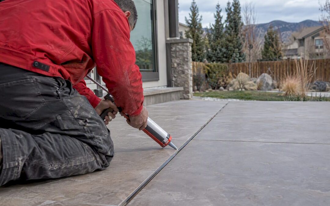 Installer sealing a joint between outdoor tiles